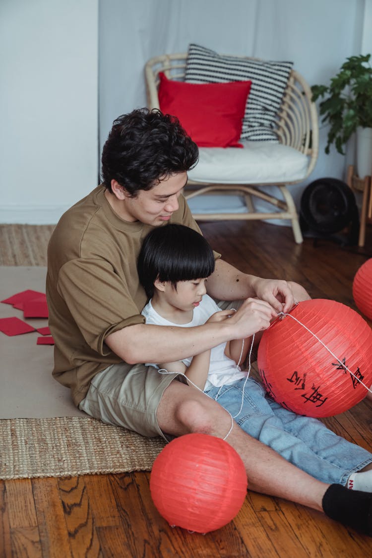 A Father And Son Tying A String On A Lantern