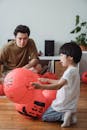 A Boy Kneeling on Wooden Floor Holding a Chinese Lantern