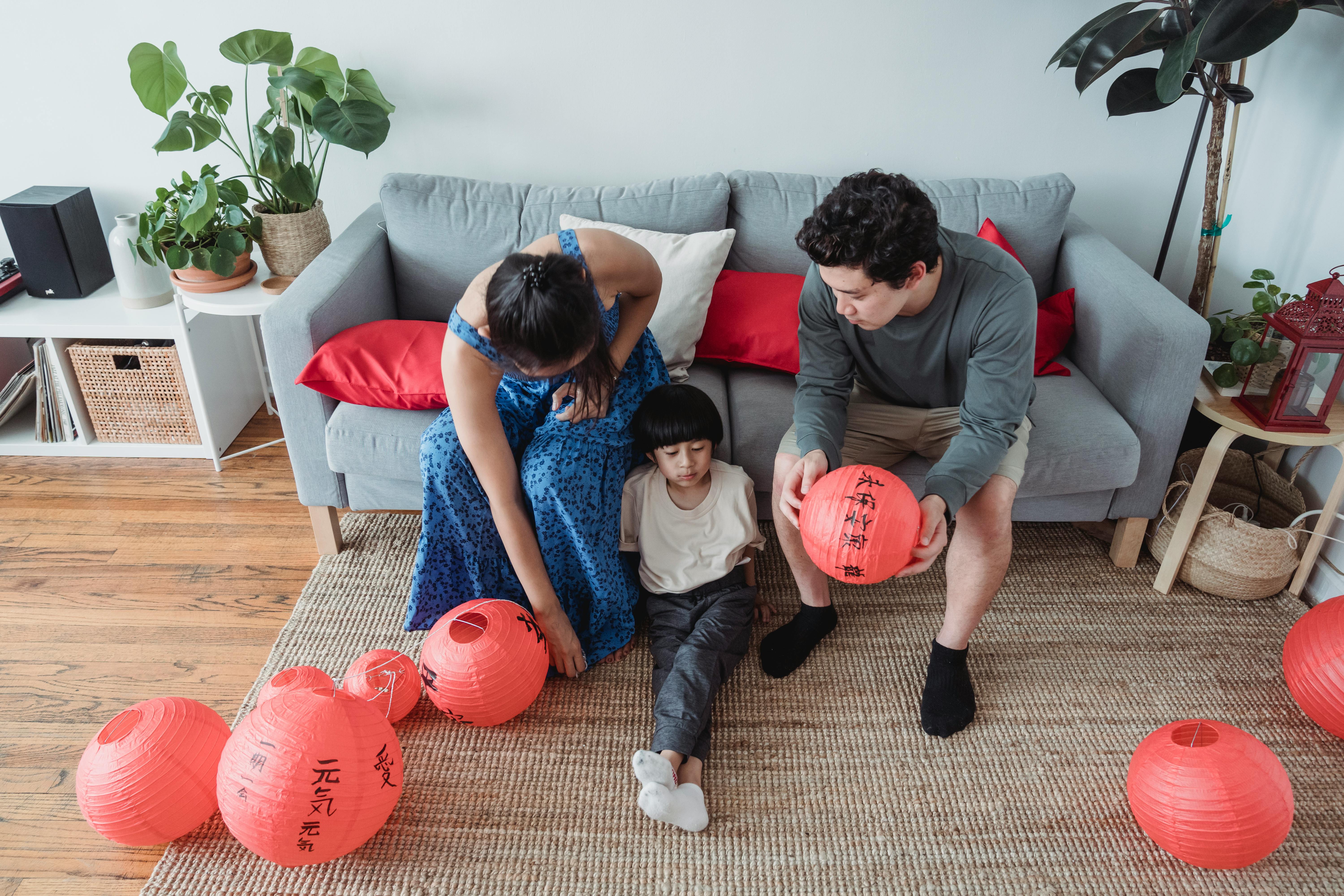 a couple sitting on the couch while looking at their son sitting on the floor