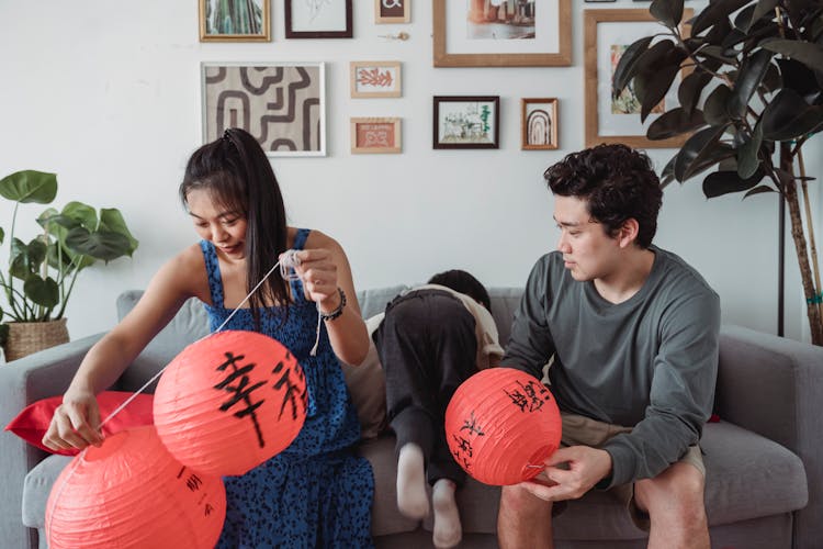 A Woman And A Man Holding Chinese Lanterns