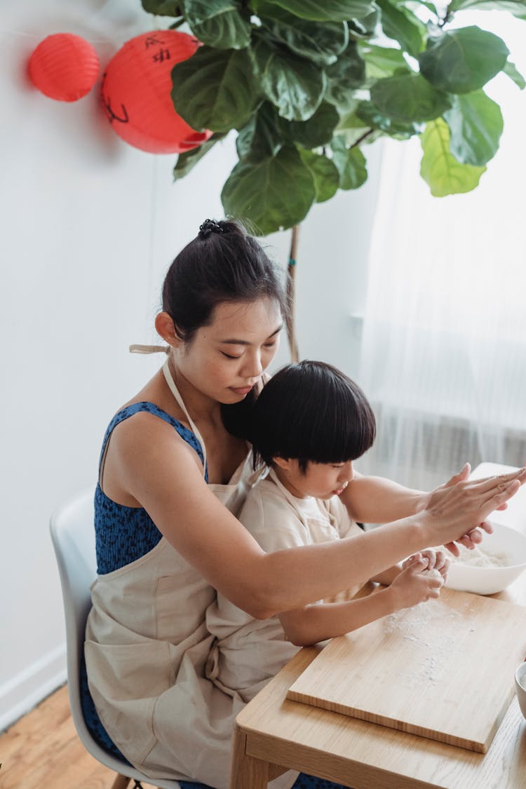 Child Sitting On Woman's Lap In Blue Top