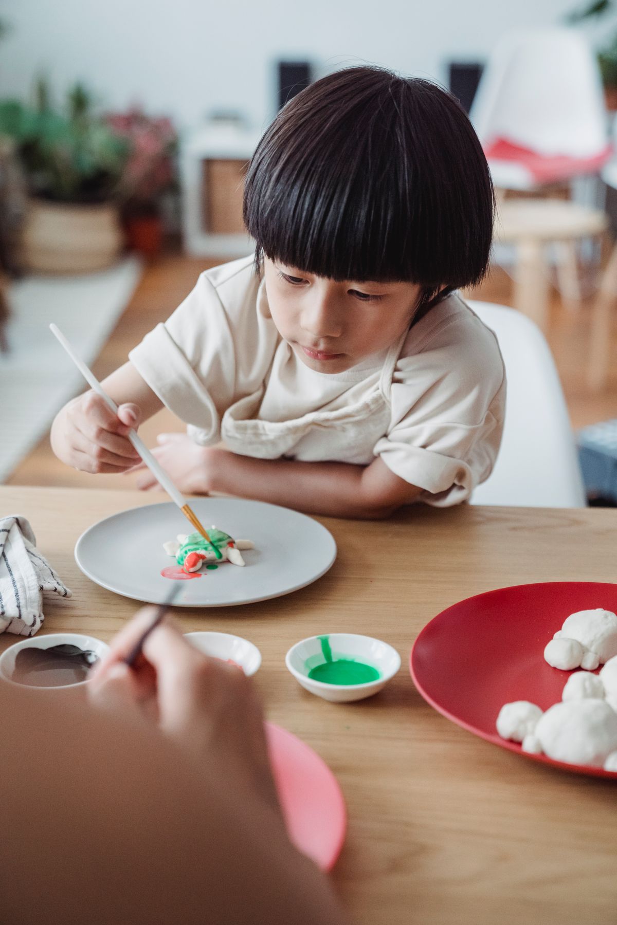 Christmas ornament ideas with a young child colouring salt dough at a wooden table