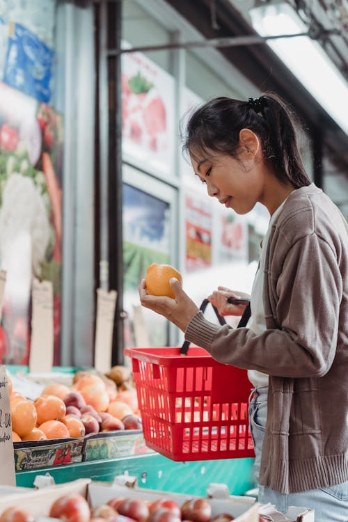 A Woman in Gray Sweater Shopping for Fruits 