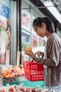 Woman in Gray Long Sleeve Shirt Holding Red Plastic Basket With Orange Fruit