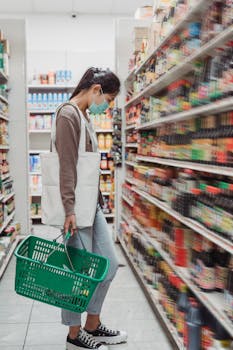 Woman in face mask shopping for condiments during Covid-19 pandemic. New normal lifestyle.