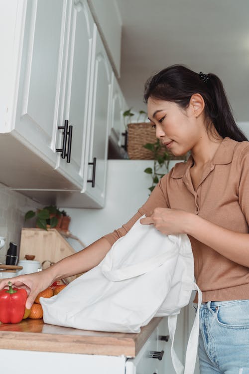 Woman Taking Groceries Out of the Bag in the Kitchen 