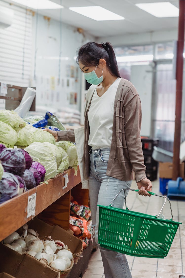 Woman Carrying A Shopping Basket And Choosing Vegetables