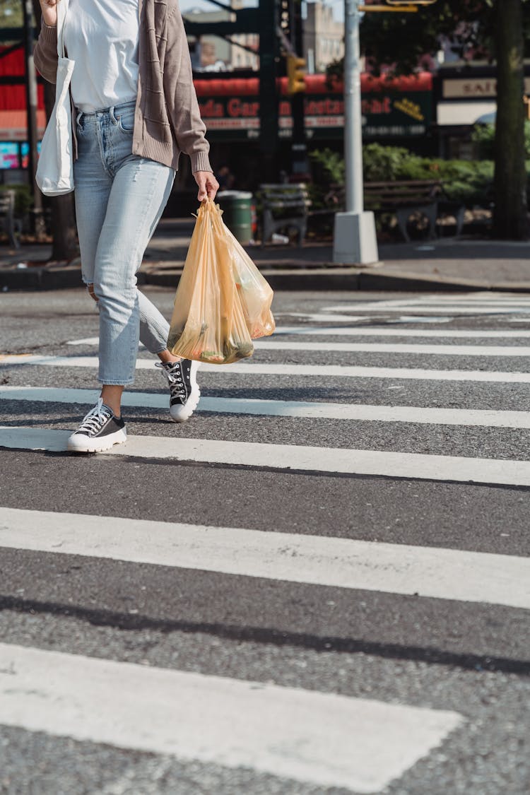 Woman Walking On A Zebra Crossing Carrying Bags