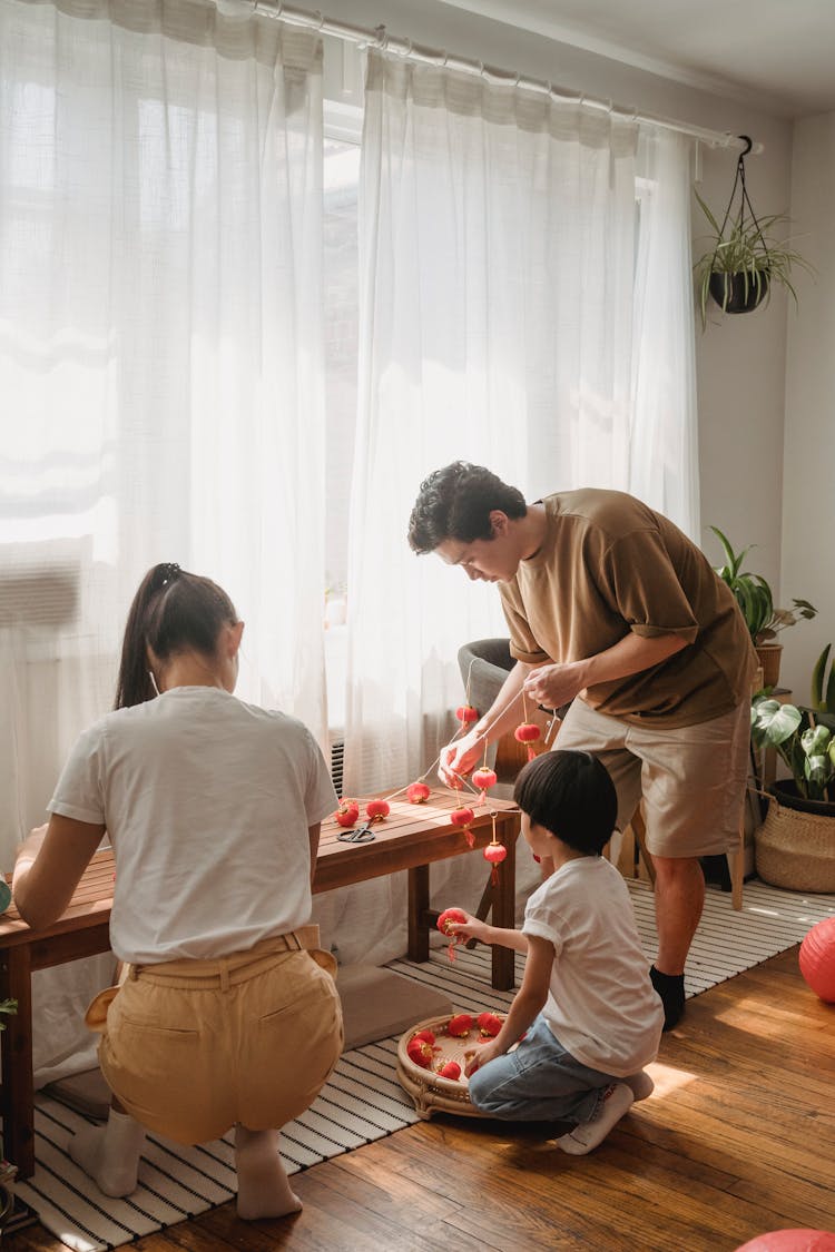 Man And Woman Helping Their Child Arranging Chinese Lanterns