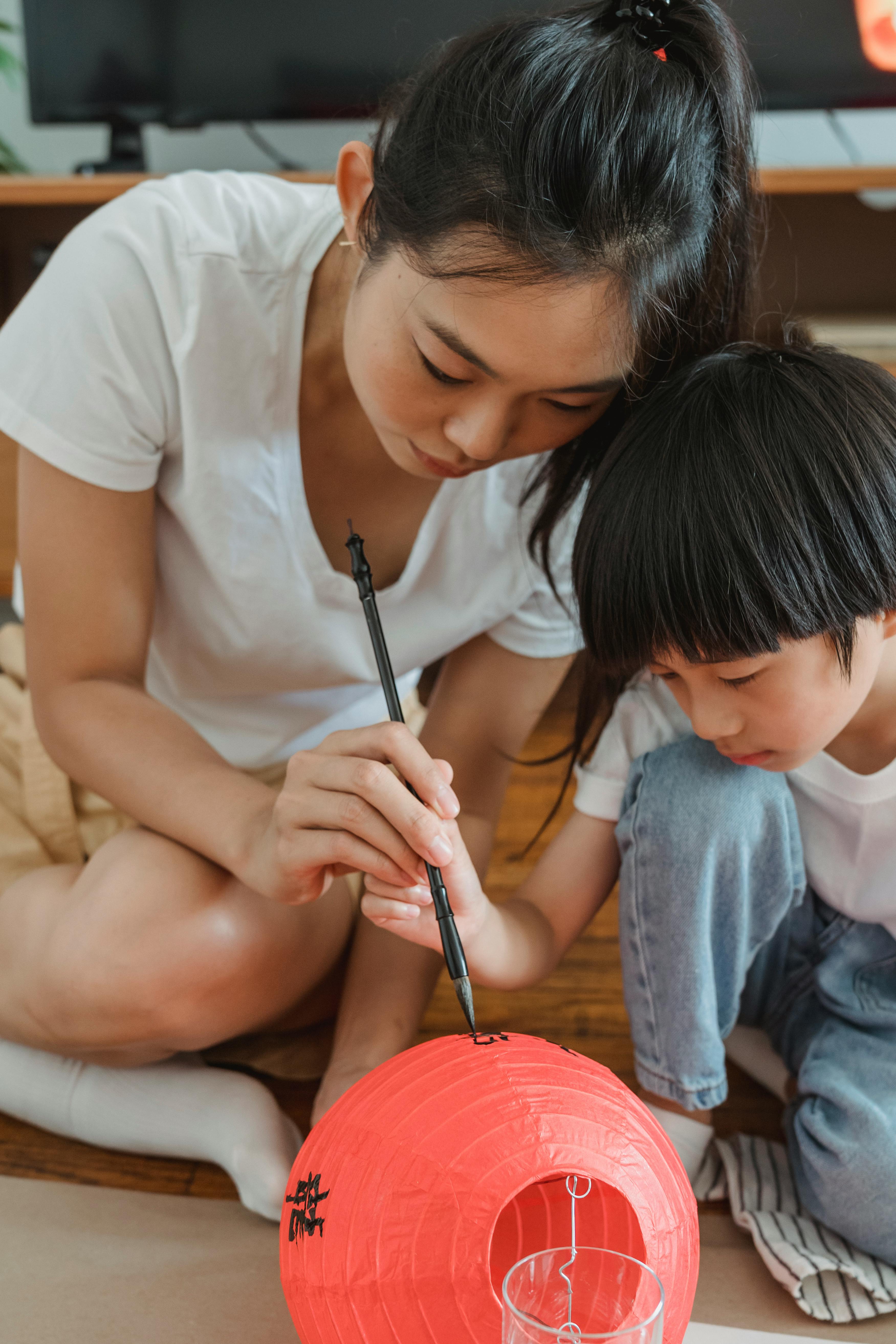 woman and a child writing on a red lantern