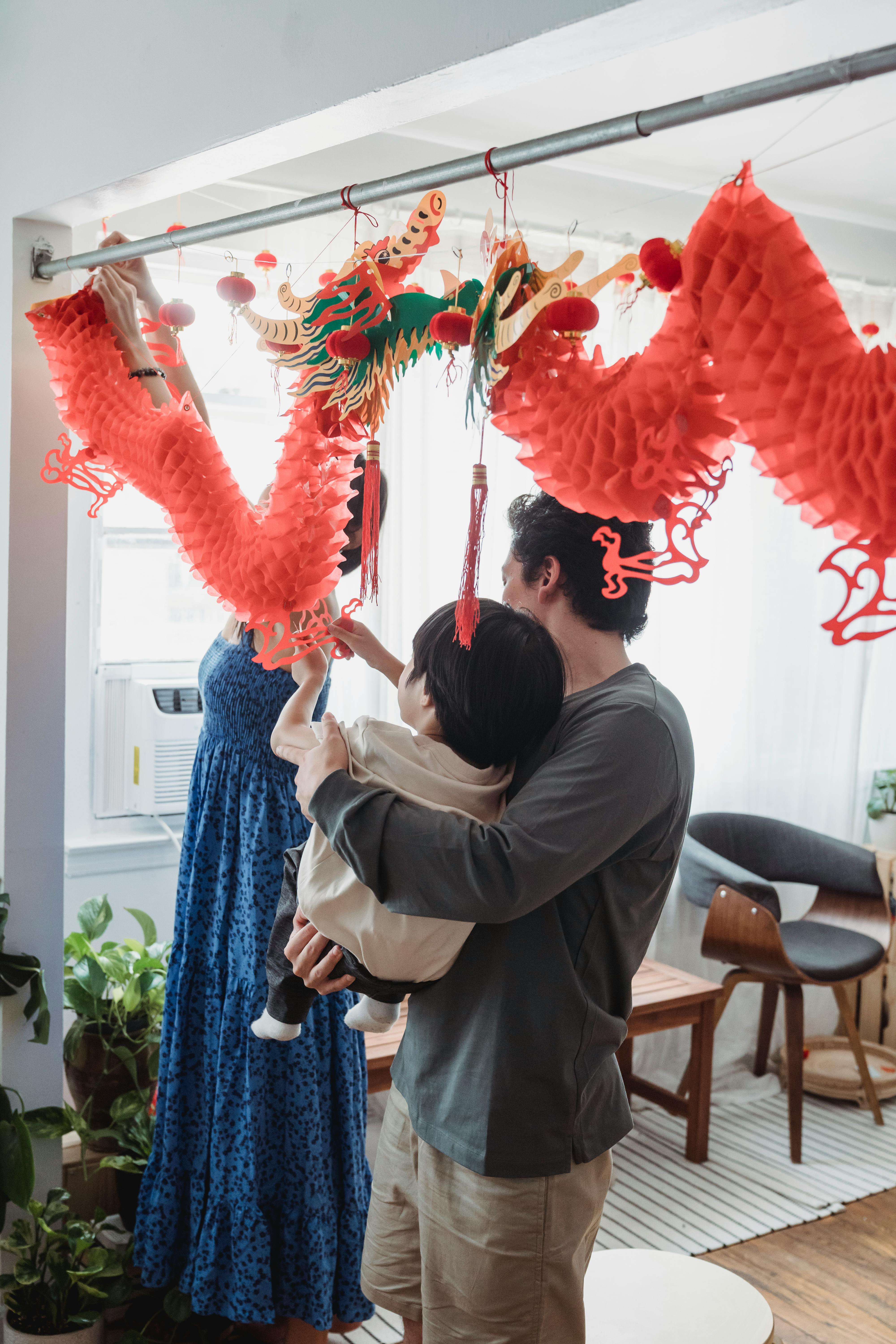 man carrying a child while decorating at home