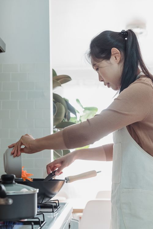 Free An Asian woman prepares a meal in a bright, modern kitchen. Indoor setting with a focus on home cooking. Stock Photo