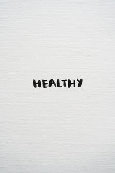 Minimalist text art with the word 'HEALTHY' on a white textured background.
