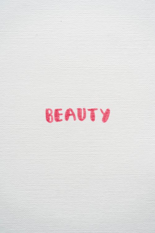 Free Simple white canvas featuring the word 'Beauty' hand-painted in red for a minimalist artistic effect. Stock Photo