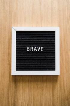 Black letter board with the word 'BRAVE' on a wooden surface. Perfect for inspiration.