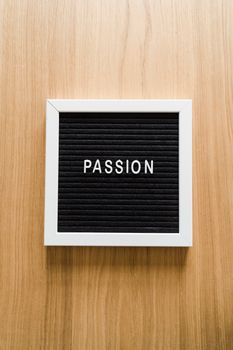 Inspirational letter board with the word 'Passion' displayed on a textured wooden surface.
