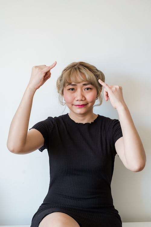 Woman in Black Top Smiling While Gesturing With Hands