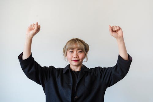 A Woman In Black Long Sleeves Raising Her Hands