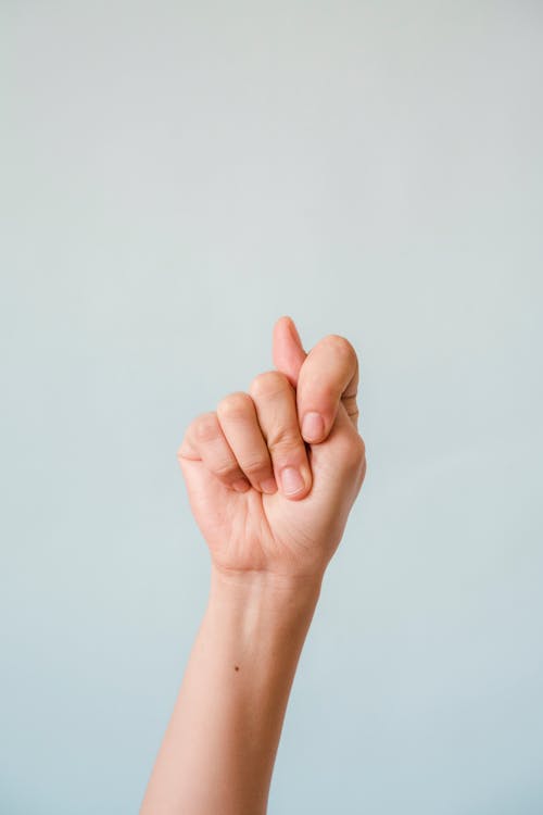 Close-up of a Raised Arm and a Hand Sign 