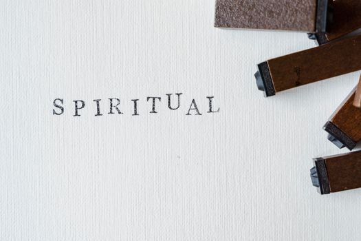 Wooden blocks spelling 'SPIRITUAL' on textured white canvas surface.