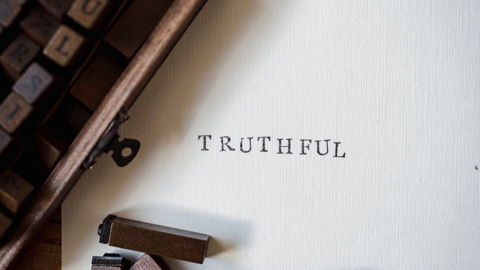Wooden letterpress type blocks arranged next to a page stamped with the word 'truthful'