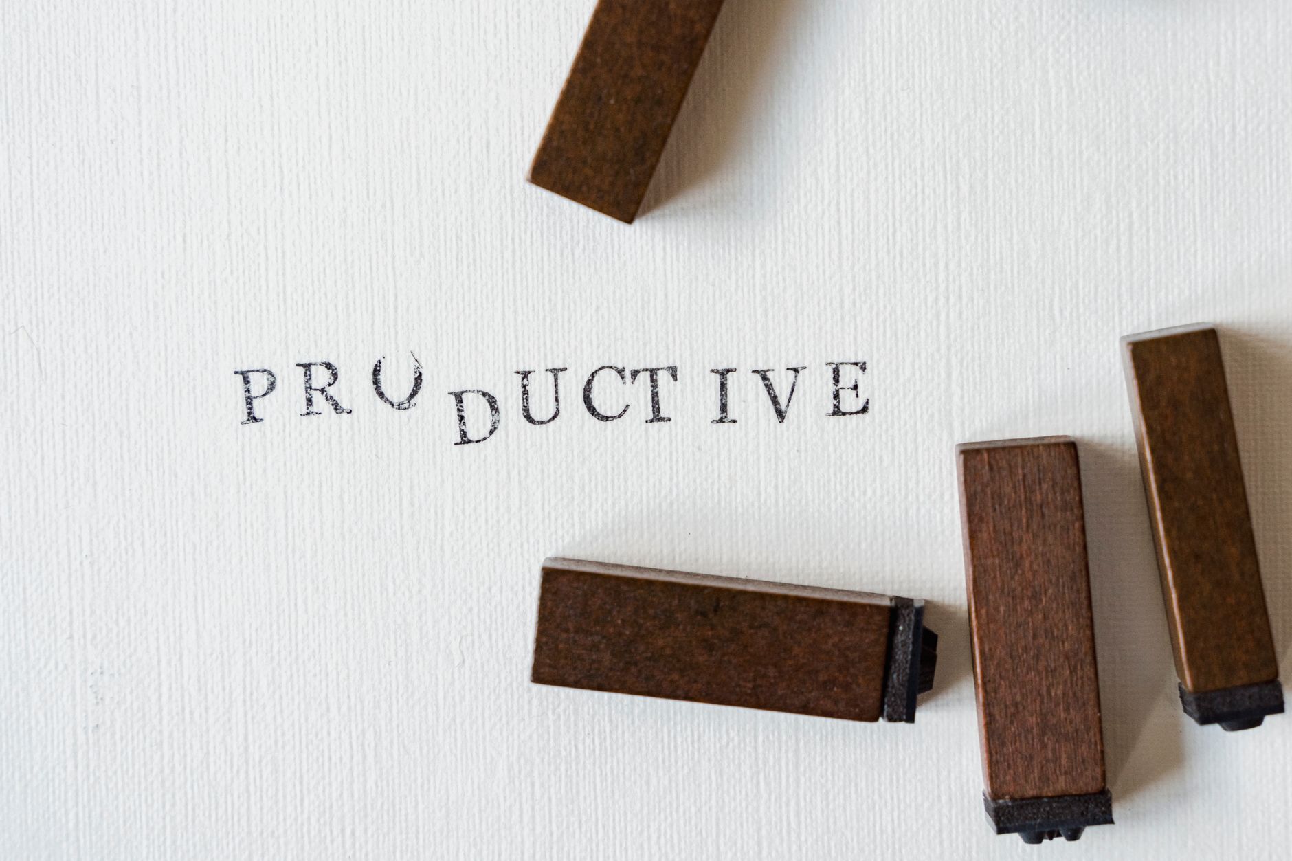 Motivational text 'Productive' stamped on canvas with wooden blocks.