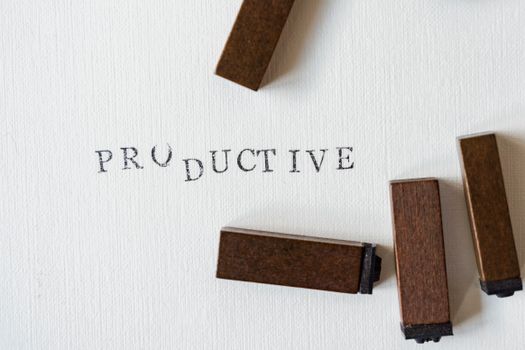 Motivational text 'Productive' stamped on canvas with wooden blocks.