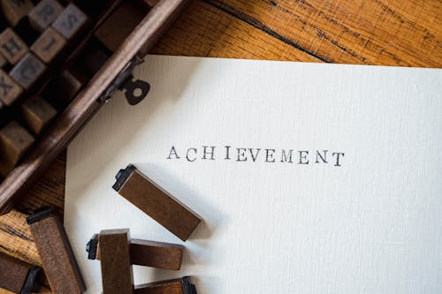 Brown Wooden Letter Blocks and Stamped Lettering on White Paper