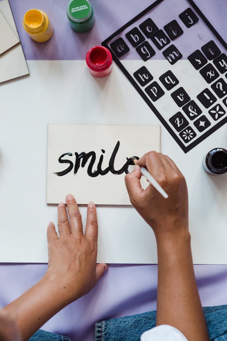 Woman Painting The Word Smile On Paper 