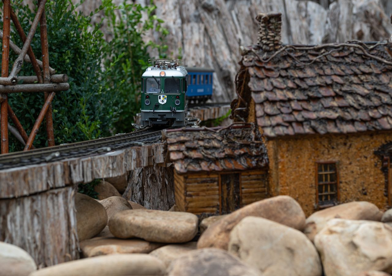 detailed model train crossing a wooden bridge amidst miniature houses