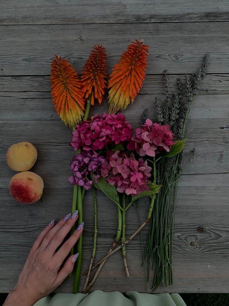 Different Kinds Of Flower Beside Peach Fruit On A Wooden Surface