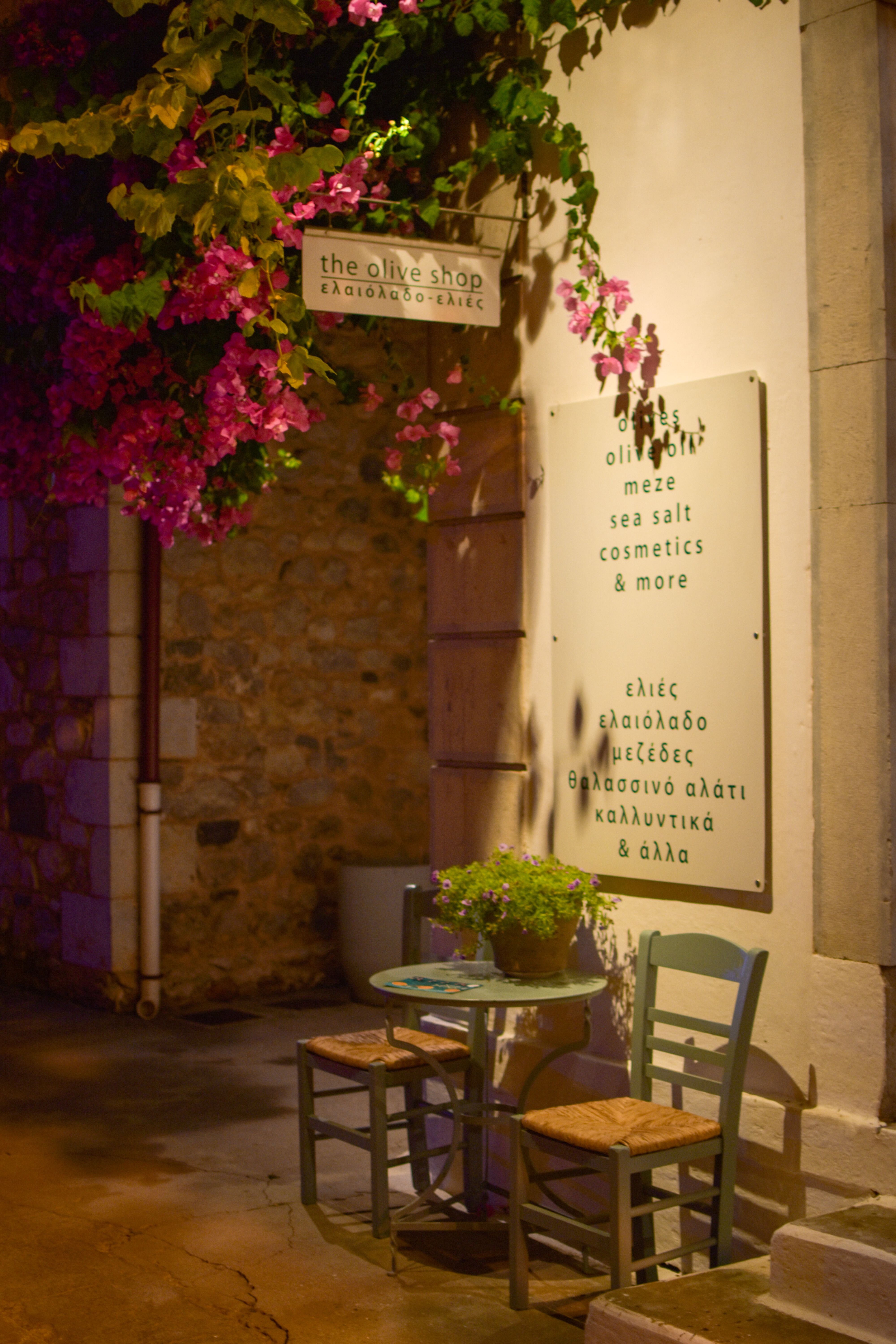 Cozy outdoor cafe corner at night, adorned with vibrant flowers and inviting chairs.