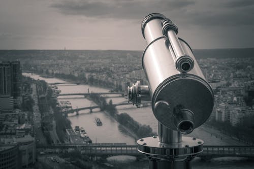 Free Grayscale Photography of Observation Telescope Overlooking City Riverbank Stock Photo