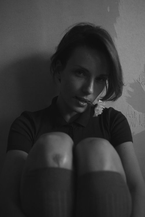 Free Moody black and white portrait of a seated woman with a flower in mouth. Stock Photo