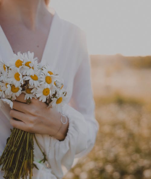 A Woman Holding a Bouquet of Daisies