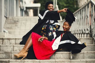 Shallow Focus Photography of Two Women in Academic Dress on Flight of Stairs