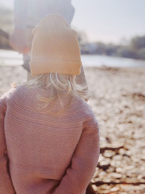 Free Back view of a young girl wearing a beanie and sweater by a riverbank in Shkotovo, Russia. Stock Photo