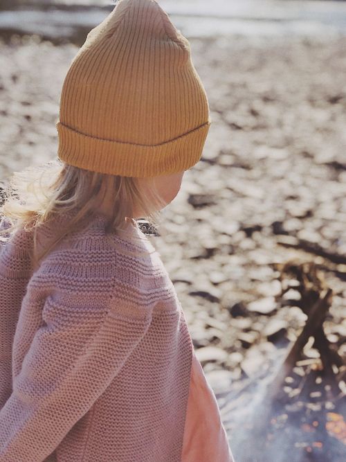 Free A child wearing a warm knitted sweater and beanie outdoors, embracing nature's serenity. Stock Photo