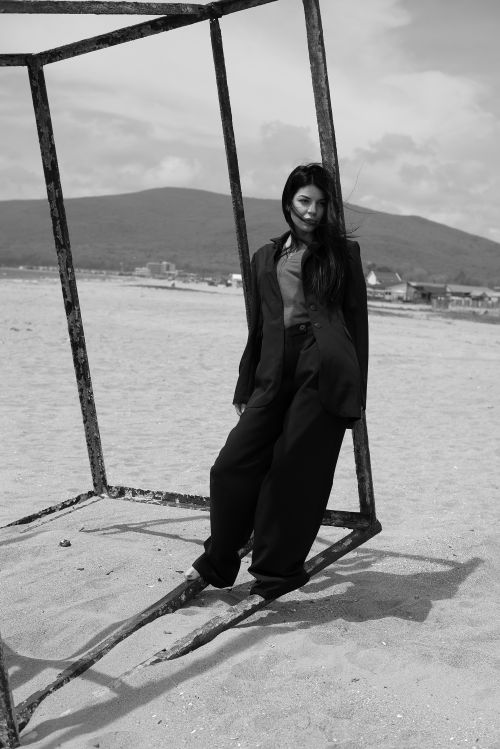 Free Stylish woman in an oversized blazer posing on a beach, black and white. Stock Photo
