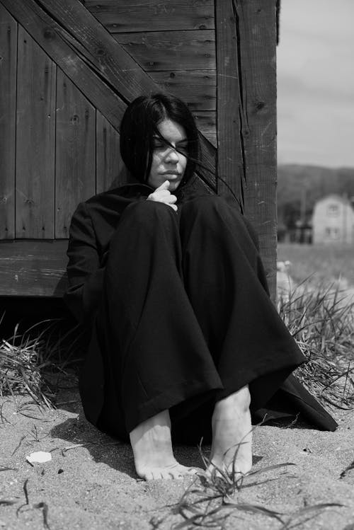 Grayscale Photo of a Woman Sitting on Sand