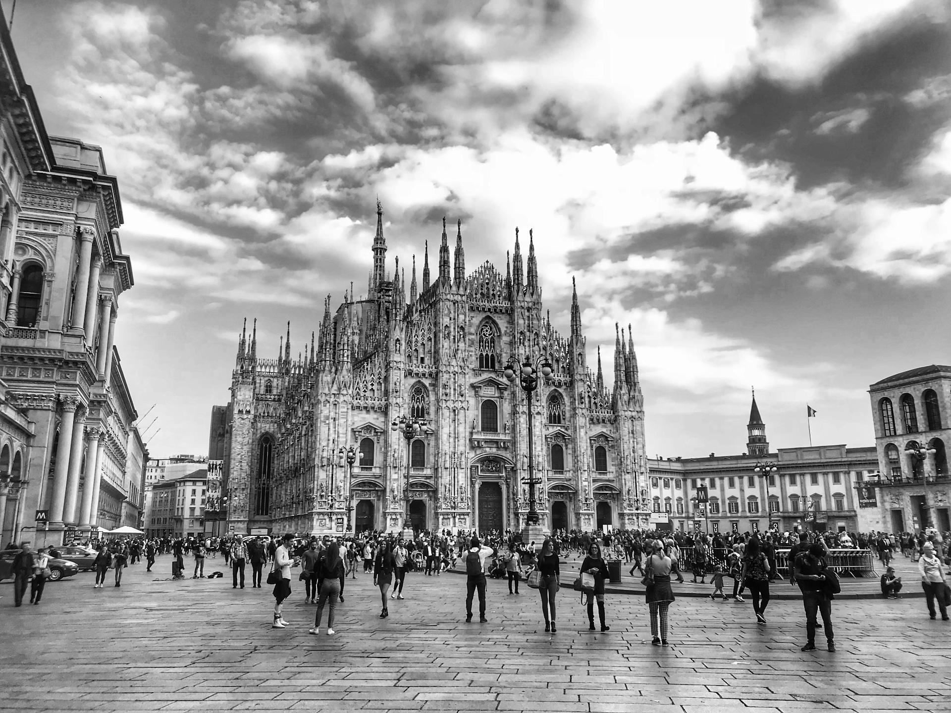 Black and white photo of Duomo di Milano with a crowd in the public square.