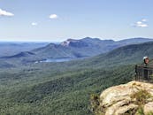 从悬崖上望去，山区景观令人叹为观止，郁郁葱葱的森林和遥远的湖泊尽收眼底