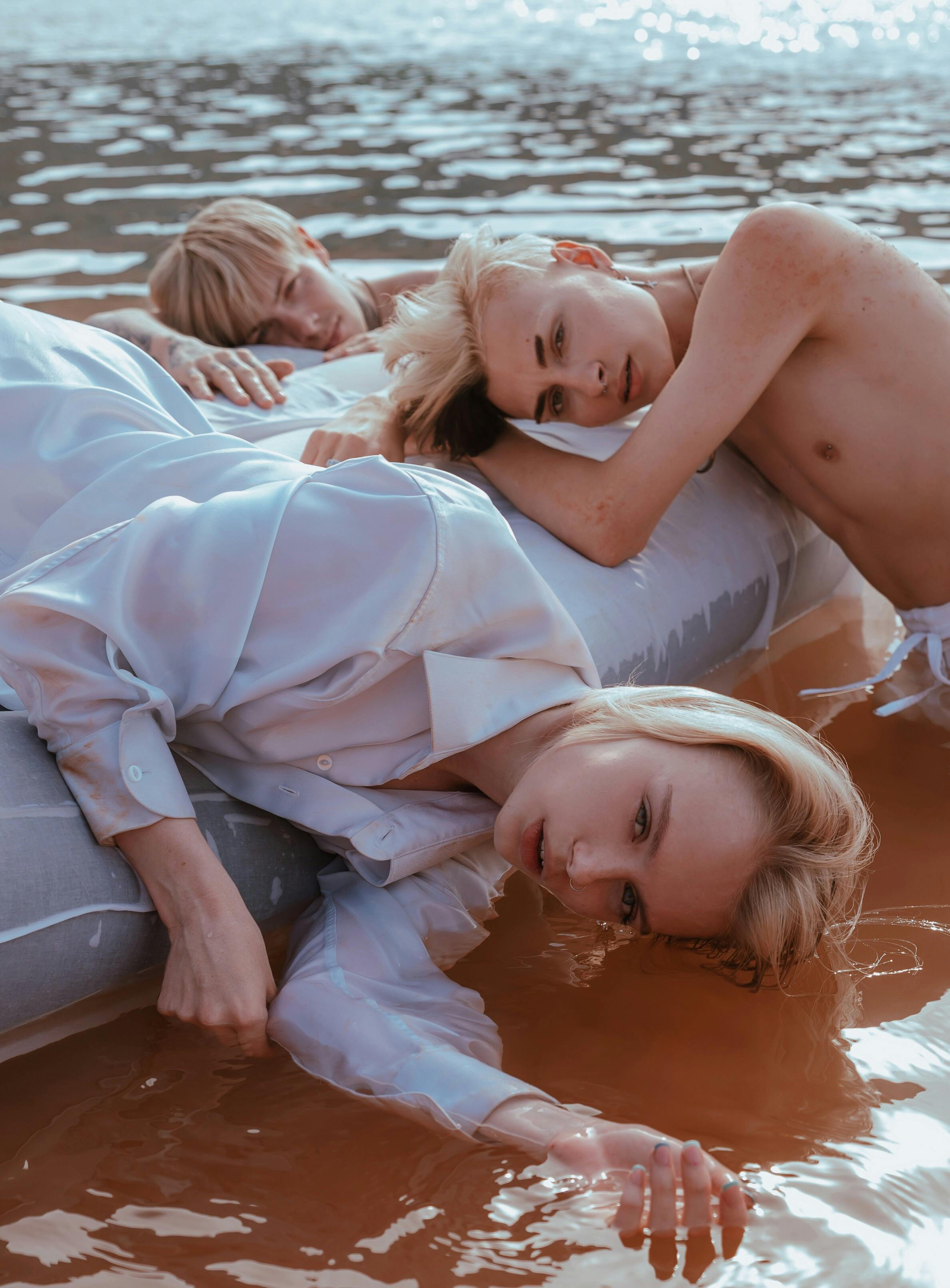 a woman in white long sleeves shirt and shirtless on a floating bed on water