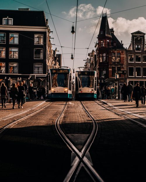 Free A vibrant scene of trams and pedestrians in historic Amsterdam, capturing urban life. Stock Photo