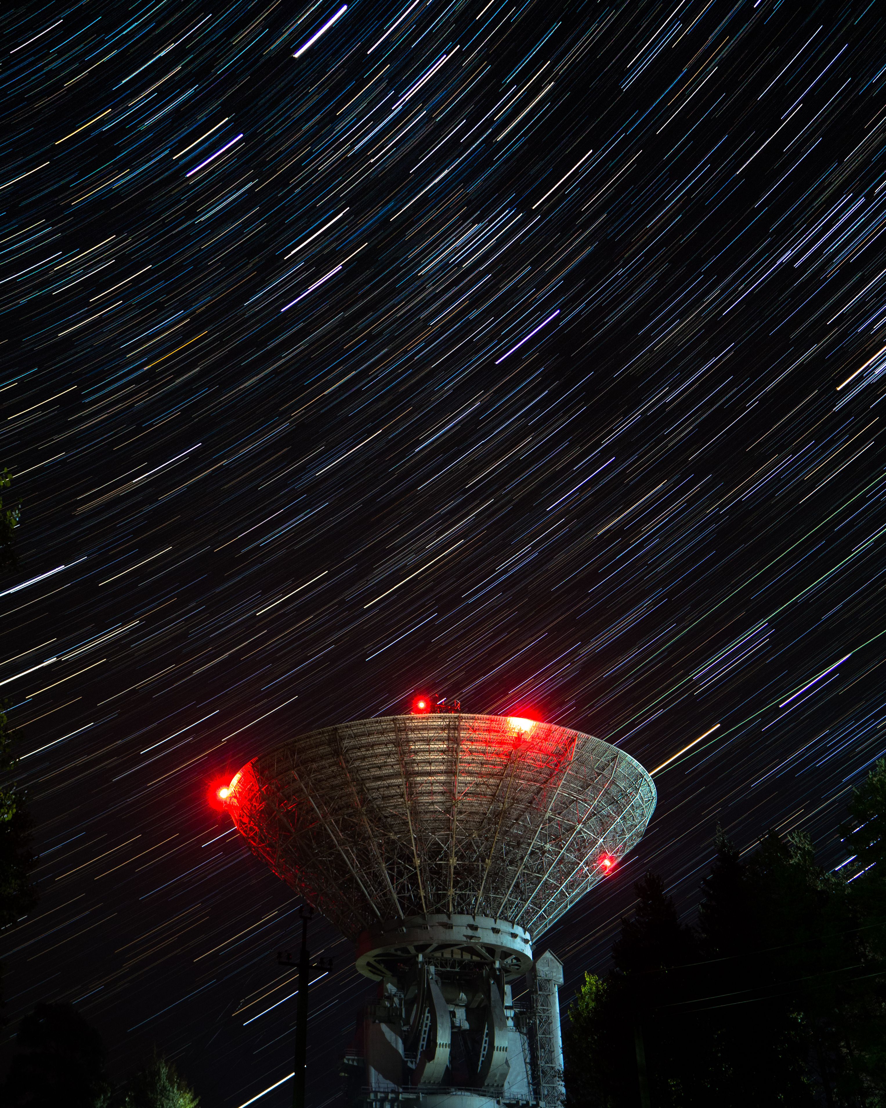 Long exposure of star trails over satellite dish, capturing night sky motion.