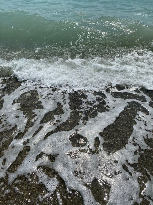 Free Lively ocean waves roll onto a rocky shoreline, creating an idyllic seaside scene. Stock Photo