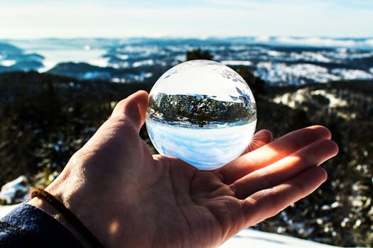 一只手持水晶球的户外特写，映出优美风景
