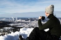 冬日阳光明媚，人们一边喝着咖啡，一边俯瞰白雪皑皑的风景