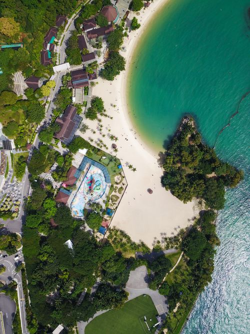 Free Stunning aerial shot of a scenic beach surrounded by lush greenery in Singapore. Stock Photo