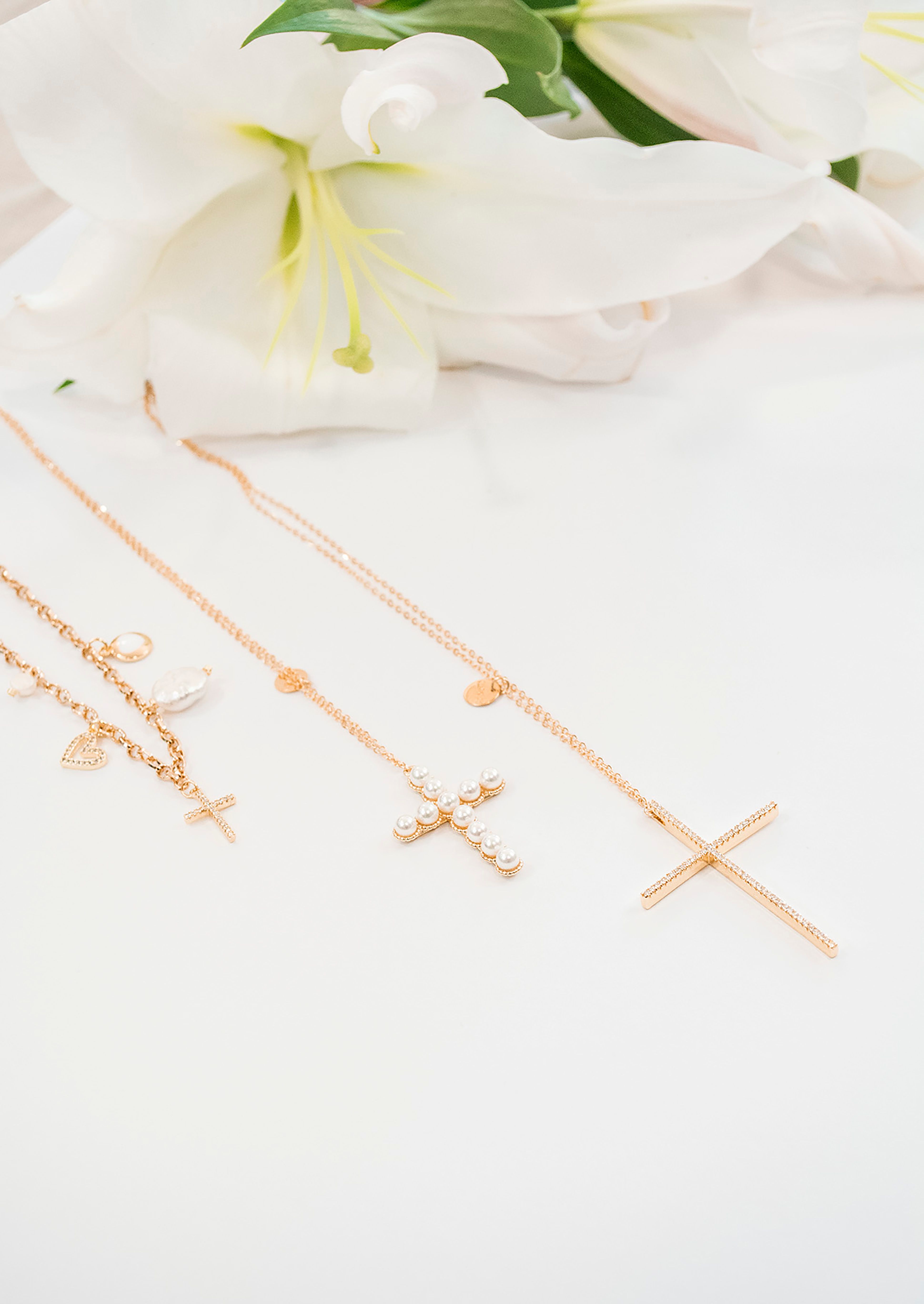 Gold cross necklaces arranged with white lilies